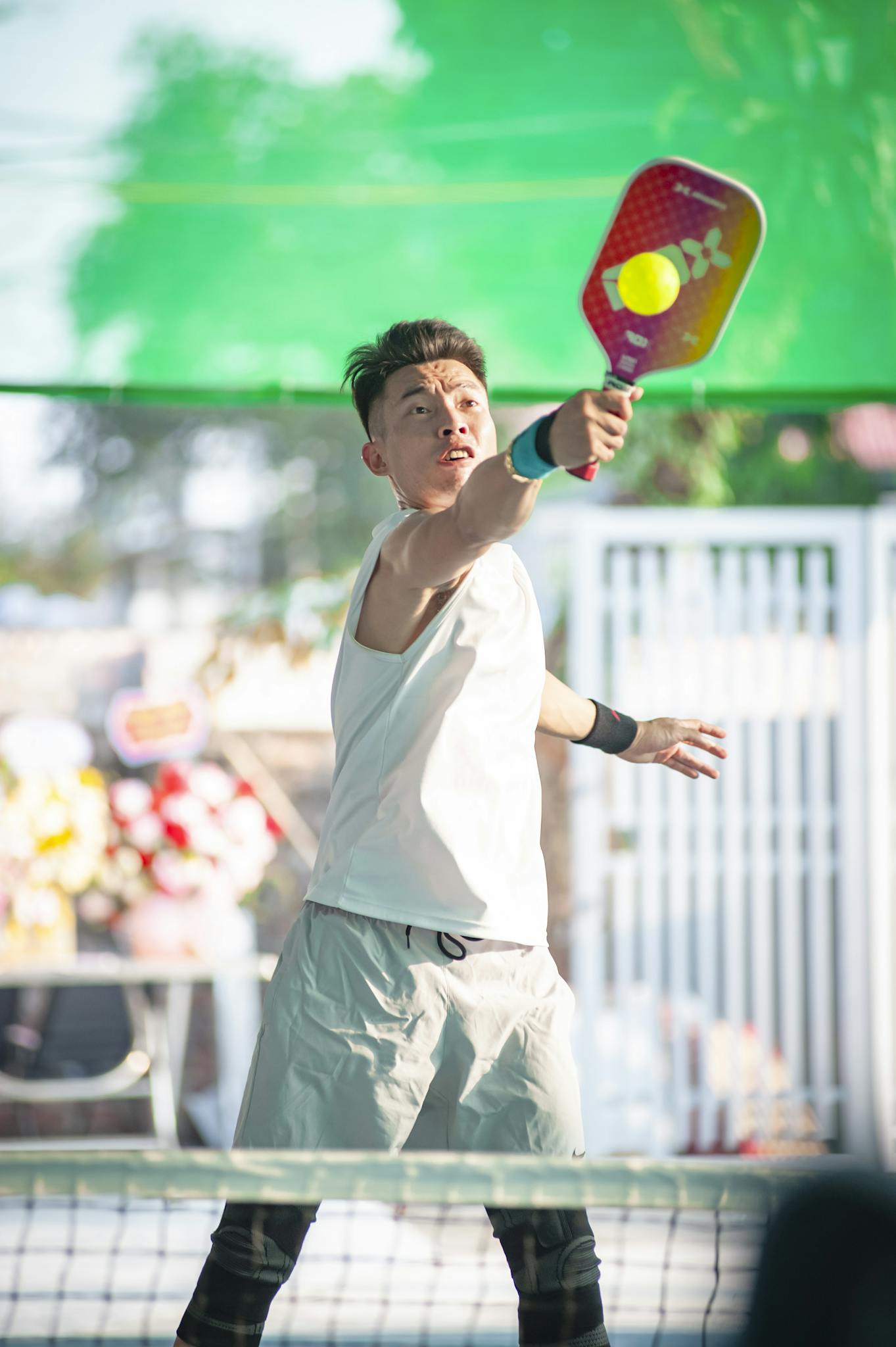 Focused young man playing pickleball outdoors in Hanoi, Vietnam.